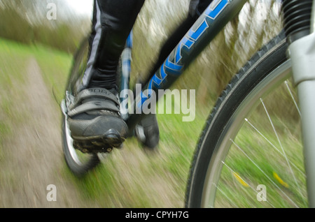 Mountainbiken mit Geschwindigkeit entlang einer schlammigen Langlauf-Route zeigt Detail Rad Fahrer Klemmen Pedale aus einem niedrigen Winkel Stockfoto