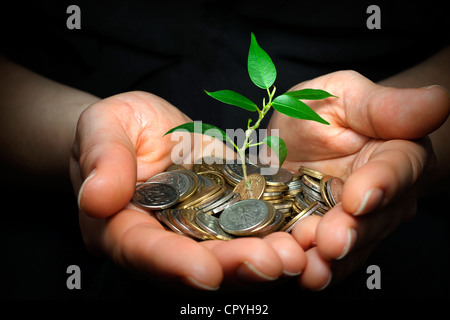 Geschäftsmann hält Pflanzen sprießen aus einer Handvoll Münzen - gute Investition und Geld-Konzept Stockfoto