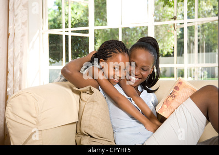 Junge Mutter mit ihrer Tochter auf einer Couch sitzend Stockfoto