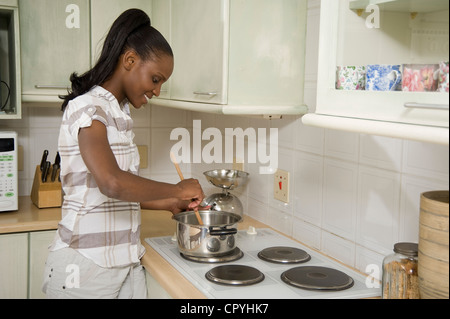 Junge afrikanische Frau, stehend auf einem Herd in der Küche Stockfoto