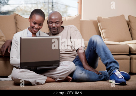 Paar, sitzen auf dem Boden mit einem Laptop, Illovo Familie, Johannesburg, Südafrika. Stockfoto