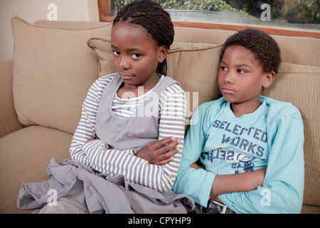 Zwei Kinder sitzen zusammen auf der Couch, Illovo Familie, Johannesburg, Südafrika. Stockfoto