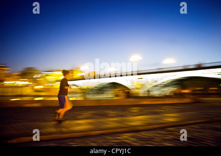 Panning Shot eines Läufers von Triana-Brücke in der Abenddämmerung, Sevilla, Spanien Stockfoto