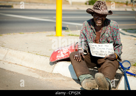 Schuss von einem afrikanischen Obdachlosen Mann sitzt auf einem Straßenrand Stockfoto