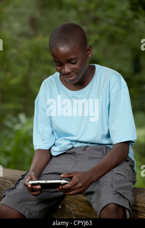Afrikanische Kind spielt mit einer Spielkonsole außerhalb Stockfoto