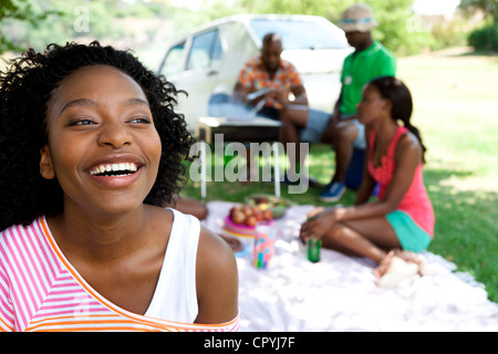 Nahaufnahme der junge schwarze Frau lächelnd, während ihre Freunde Braai im Hintergrund Stockfoto