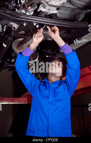 Afrikanischen Mechaniker stehen unter einem Auto, arbeiten am Motor Stockfoto