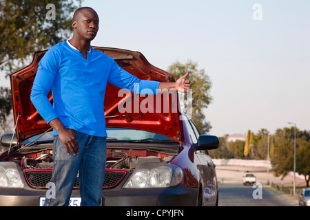 Afrikanischer Mann stand vor seinem kaputten Auto, Trampen Stockfoto
