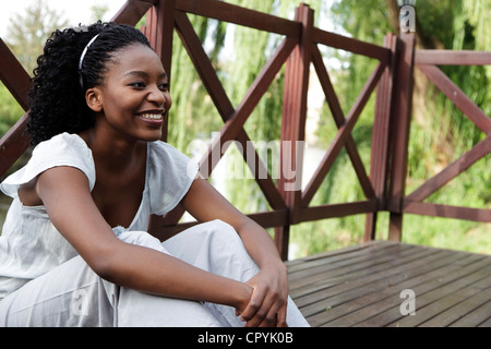 Junge afrikanische Frau sitzt auf einem Holzdeck Stockfoto