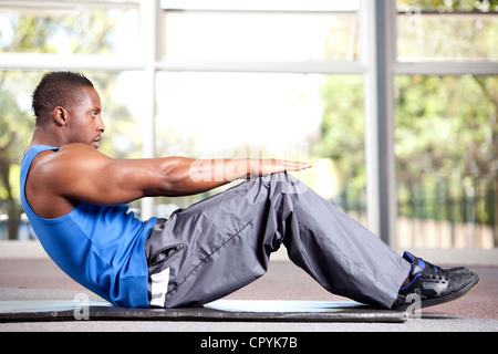 Junge muskulöse schwarzer Rüde erstreckt sich in einem Fitnessstudio Stockfoto