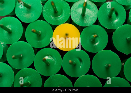 Eine gelbe unter vielen grünen Push-pins Stockfoto