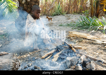 Ein Junge, der nicht zur Schule gehen kocht eine Yam Knolle in ein Lagerfeuer während der Arbeit im Feld in Djorbana, Region Zanzan Stockfoto