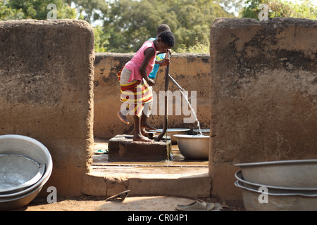 Kinder füllen Sie Behälter mit Wasser aus einer kommunalen Fuß aktiviert Pumpe im Dorf Kiendi-Walogo, Zanzan region Stockfoto