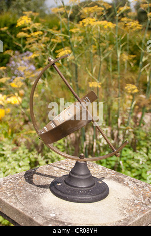 Messing-Sonnenuhr auf Steinsockel im Garten Stockfoto