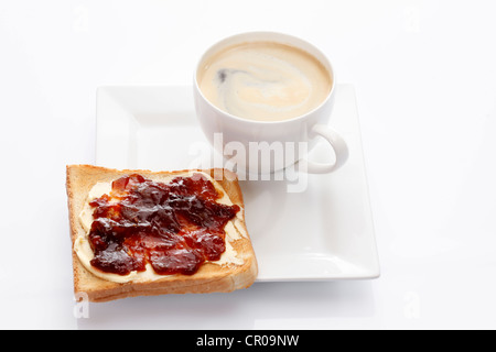 Porzellanteller mit einer Tasse Kaffee und Toast mit Erdbeermarmelade Stockfoto