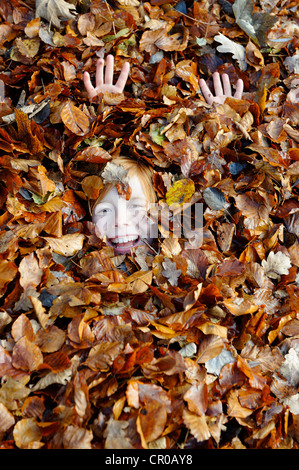 Jungen spielen mit Blättern im Herbst Stockfoto