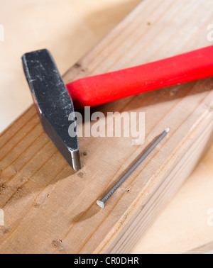 Hammer und Nagel auf einem Holzbalken Stockfoto