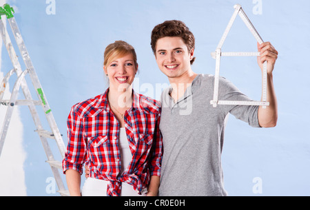 Junges Paar hält eine Faltung des Tischlers Herrscher in der Form eines Hauses Stockfoto