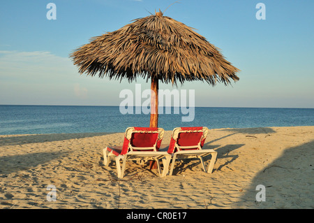 Leere Sonnenliegen unter einem Sonnenschirm am Strand von Playa Ancón in der Nähe von Trinidad, Kuba, Caribbean Stockfoto