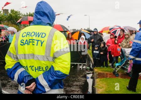 Crowd Safety Officer Wachmann mit einer Menschenmenge bei starkem Regen Stockfoto