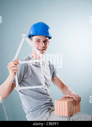 Junge Handwerker halten eine Faltung des Tischlers Herrscher in der Form eines Hauses Stockfoto