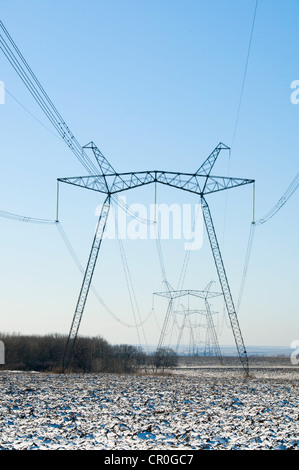 Linie der elektrischen Masten im Winter schneebedeckten Feld Stockfoto