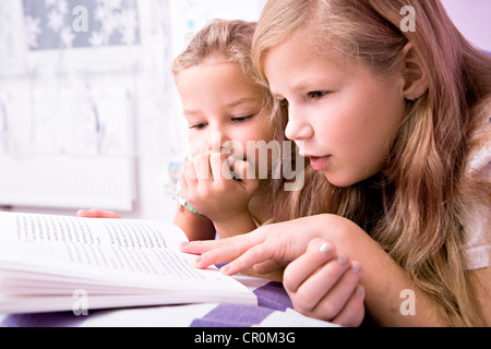 Zwei Mädchen, Schwestern lesen im Bett Stockfoto