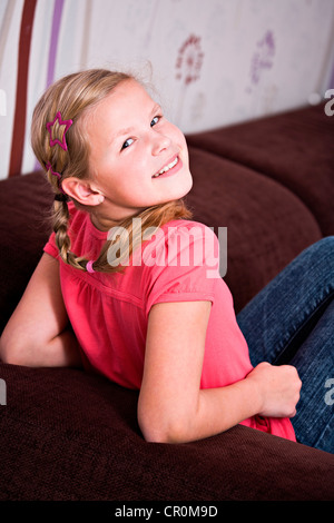 Mädchen, 11, sitzen auf einem sofa Stockfoto