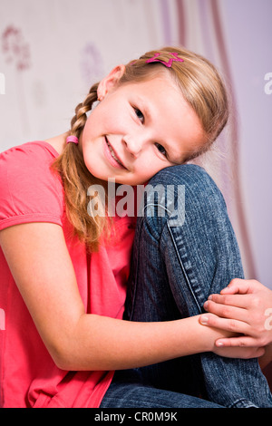 Mädchen, 11, mit dem Kopf ruht auf ihrem Knie sitzt Stockfoto