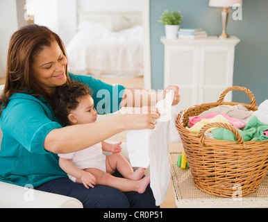 Mischlinge Mutter Falten, Wäsche und halten baby Stockfoto