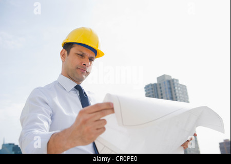 Gemischte Rassen Geschäftsmann Blick auf Blaupausen auf Baustelle Stockfoto