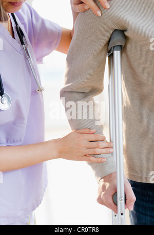 USA, New Jersey, Jersey City, Nahaufnahme von Ärztin hilft Patienten mit Krücke Stockfoto