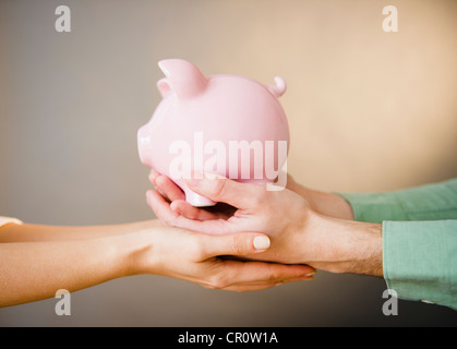 Nahaufnahme eines Mannes und Weibes Hände halten Sparschwein, Studio gedreht Stockfoto