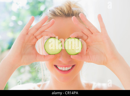USA, New Jersey, Jersey City, Porträt der lächelnde junge Frau Abdeckung Augen mit Gurkenscheiben Stockfoto