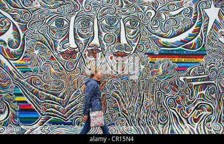 BERLIN, DEUTSCHLAND. Eine Frau zu Fuß Vergangenheit eine Wandbild an der East Side Gallery, einem Abschnitt der Berliner Mauer von Künstlern gestaltet. 2012 Stockfoto