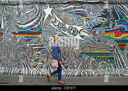 BERLIN, DEUTSCHLAND. Eine Frau zu Fuß Vergangenheit eine Wandbild an der East Side Gallery, einem Abschnitt der Berliner Mauer von Künstlern gestaltet. 2012 Stockfoto