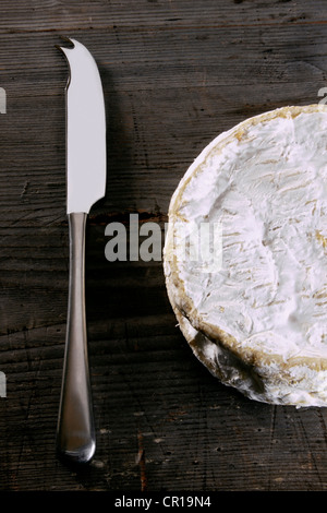 Camembert mit einem Käsemesser auf einer rustikalen Holzoberfläche Stockfoto