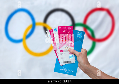 Person, die ihre Olympia-Tickets für die Spiele 2012 in London mit der Olympischen Flagge im Hintergrund Stockfoto
