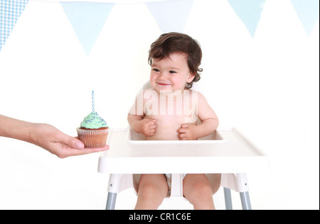 Baby schauen gespannt auf seine cupcake Stockfoto