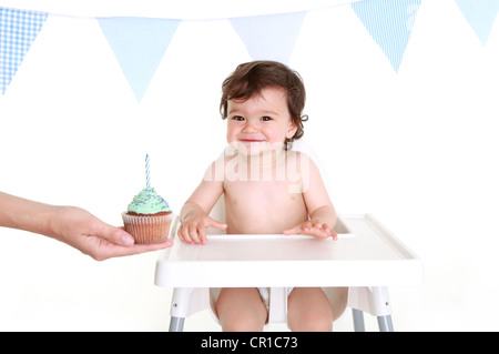 Baby schauen begeistert von cupcake Stockfoto