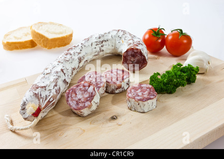 Gourmet-Salami, Premium-Salami mit Baguette, Knoblauch Tomaten und Petersilie auf einem Holzbrett Stockfoto