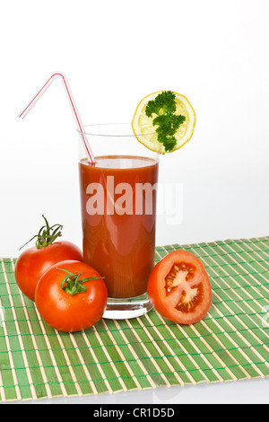 Tomatensaft in einem Glas mit Tomaten und Zitrone Stockfoto