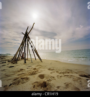 Log-Tipi am Sandstrand Stockfoto