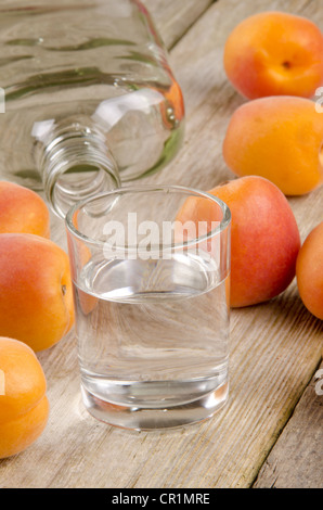 hausgemachte Obstbrände in ein Glas und frischen Aprikosen im Hintergrund Stockfoto