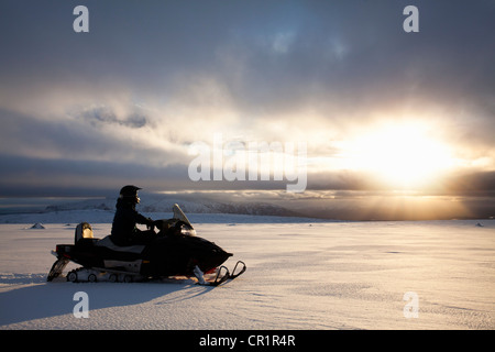 Mann fahren mit Motorschlitten in schneebedecktes Feld Stockfoto