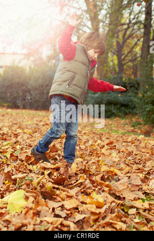 Junge spielt im Herbstlaub Stockfoto