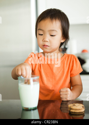 Mädchen Tauchen Cookie in Milchglas (2-3) Stockfoto