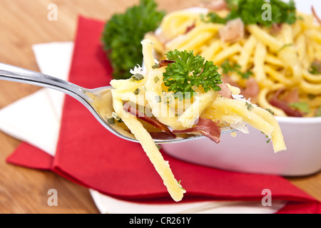 Käse-Spätzle in einer Schüssel mit Anteil an Gabel (auf hölzernen Hintergrund) Stockfoto