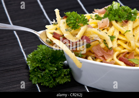 Portion Käse Spätzle in einer Schüssel mit Anteil an Gabel (auf schwarze Tischdecke) Stockfoto