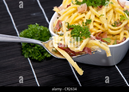 Portion Käse Spätzle in einer Schüssel mit Anteil an Gabel (auf schwarze Tischdecke) Stockfoto